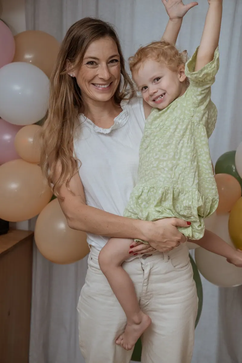 Mutter mit Kleinkind vor Luftballons