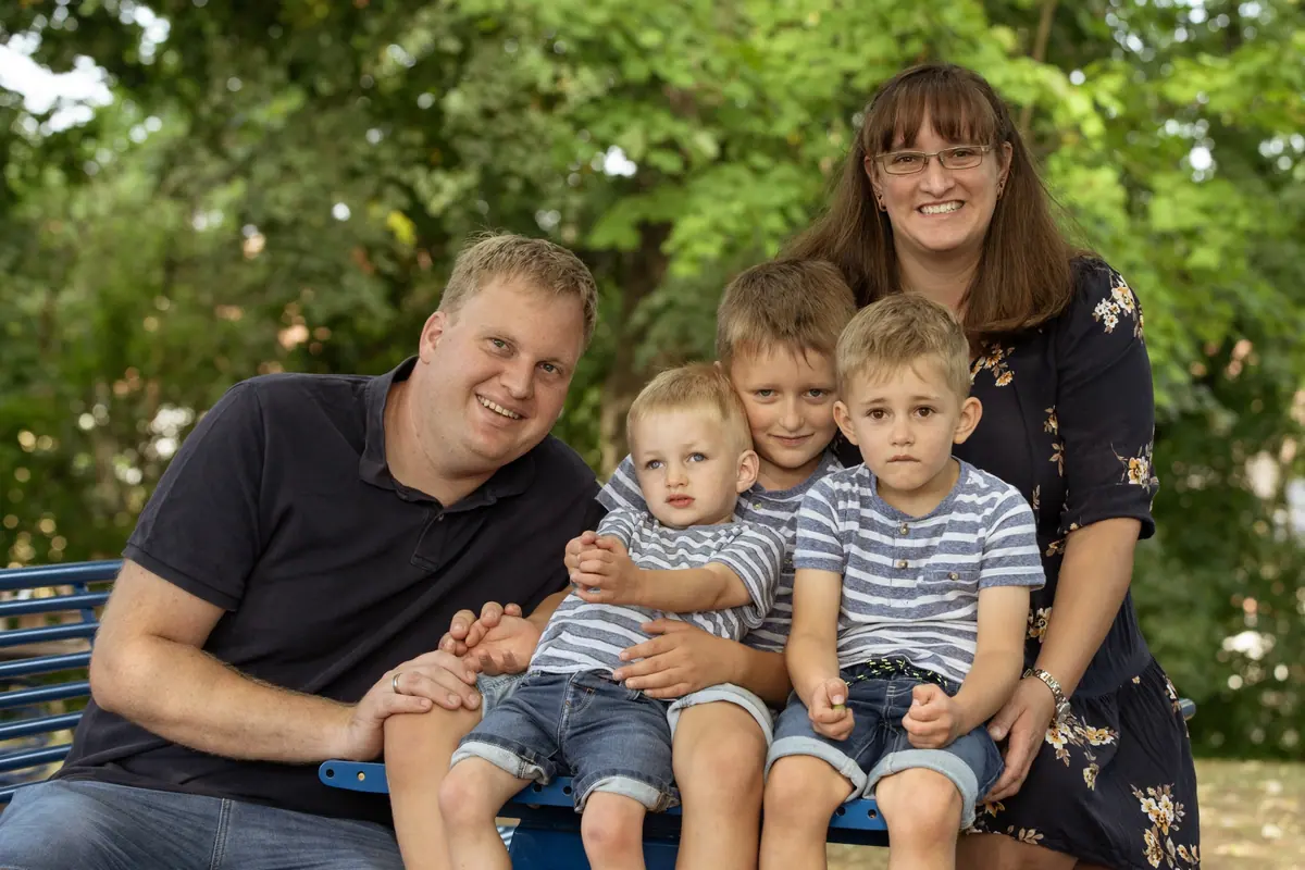 Familie mit drei Jungen auf einer Parkbank
